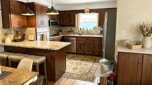A kitchen with wooden cabinets, a central island, pendant lighting, and a window. - Remodeled House with Pool on Quiet cul-de-sac!  Walk to beach on Bay! (Shalimar)