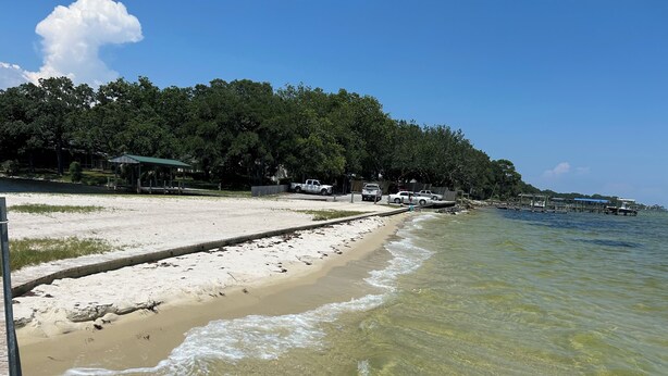 A beach with clear water, a sandy shore, and a forested area in the background. - Remodeled House with Pool on Quiet cul-de-sac!  Walk to beach on Bay! (Shalimar)