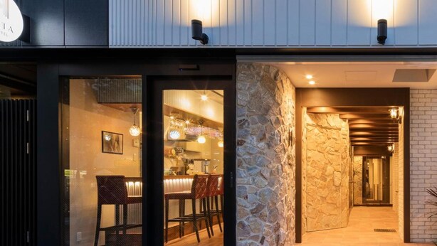 A modern building with a restaurant entrance, stone wall, and a visible bar area. - Asta Hotel (Tokyo)