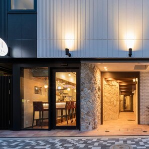 A modern building with a restaurant entrance, stone wall, and a visible bar area. - Asta Hotel (Tokyo)