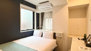 A hotel room with a bed, a desk, a window with curtains, and an air conditioning unit. - Asta Hotel (Tokyo)