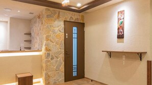 A hotel lobby with a stone wall, a reception desk, a door, and a wall-mounted shelf. - Asta Hotel (Tokyo)