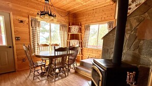 Ein gemütliches Blockhaus-Interieur mit Kamin aus Stein, Holzespeisesaal und Stühlen.