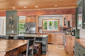 Eine moderne Küche mit Holzschränken, einem Edelstahlkühlschrank und einer großen Kochinsel.
