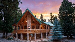 A log cabin with a stone chimney, a balcony, and a view of the surrounding forest. - Great Escape Retreat! Hot Tub & Fire Pit! (Kane County)