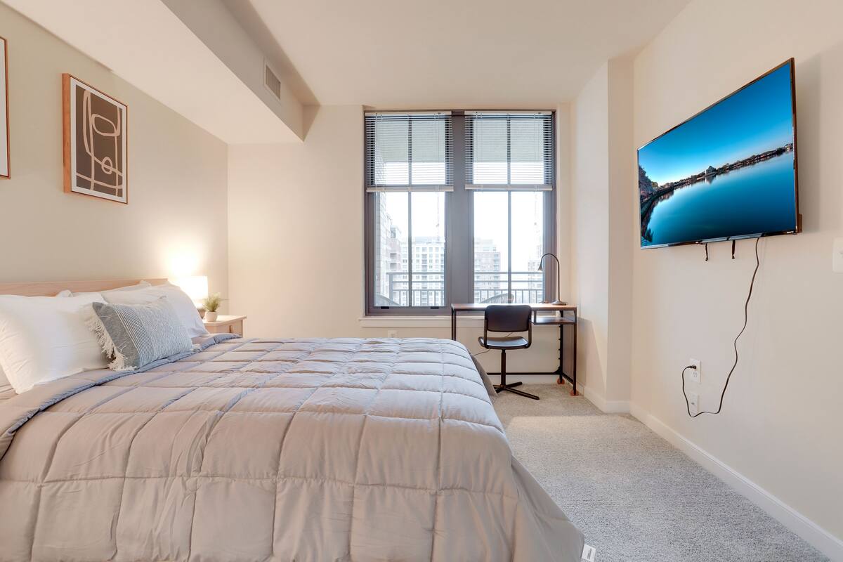 Une chambre à coucher avec un lit, un bureau et une grande fenêtre.