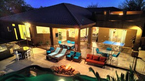 Un espacio al aire libre techado con sillones de descanso, piscina y una parrilla.