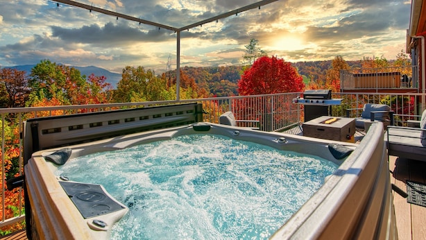 Een jacuzzi op een terras met een prachtig uitzicht op herfstkleuren en bergen.