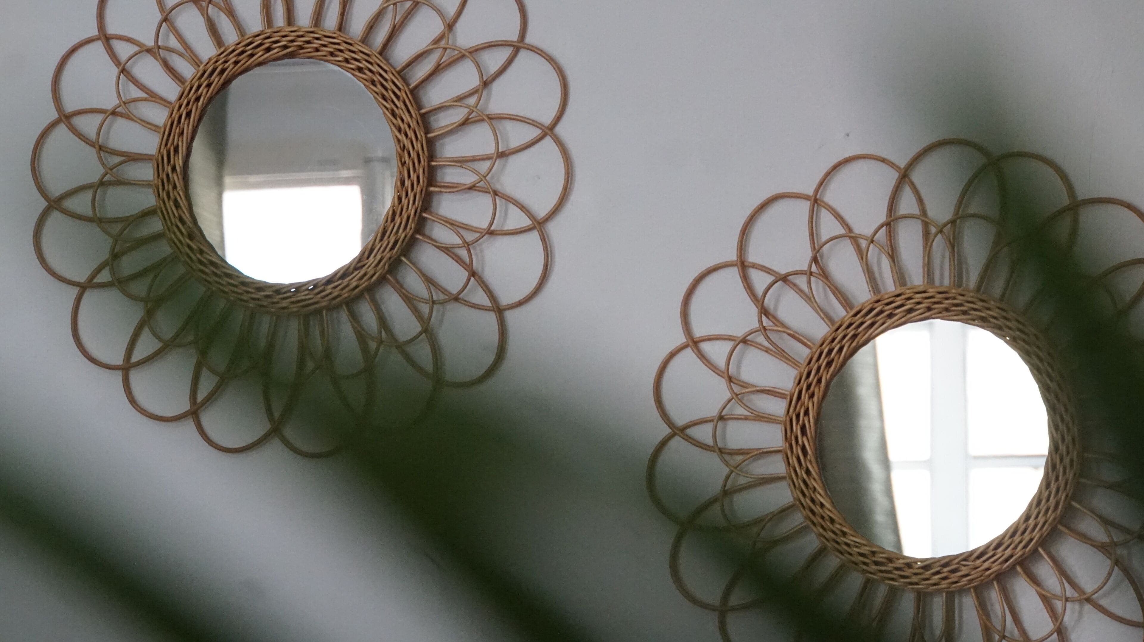 Due specchi fissati alla parete con cornice circolare e decorazioni intrecciate.