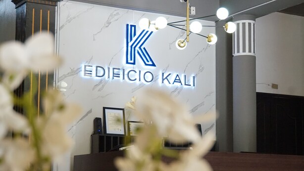 A reception desk with a marble wall and a sign reading "EDIFICIO KALI". - Kali Hotel  (Santa Ana)