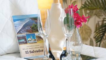A book titled 'El Salvador' on a table with three glasses and a vase with flowers.