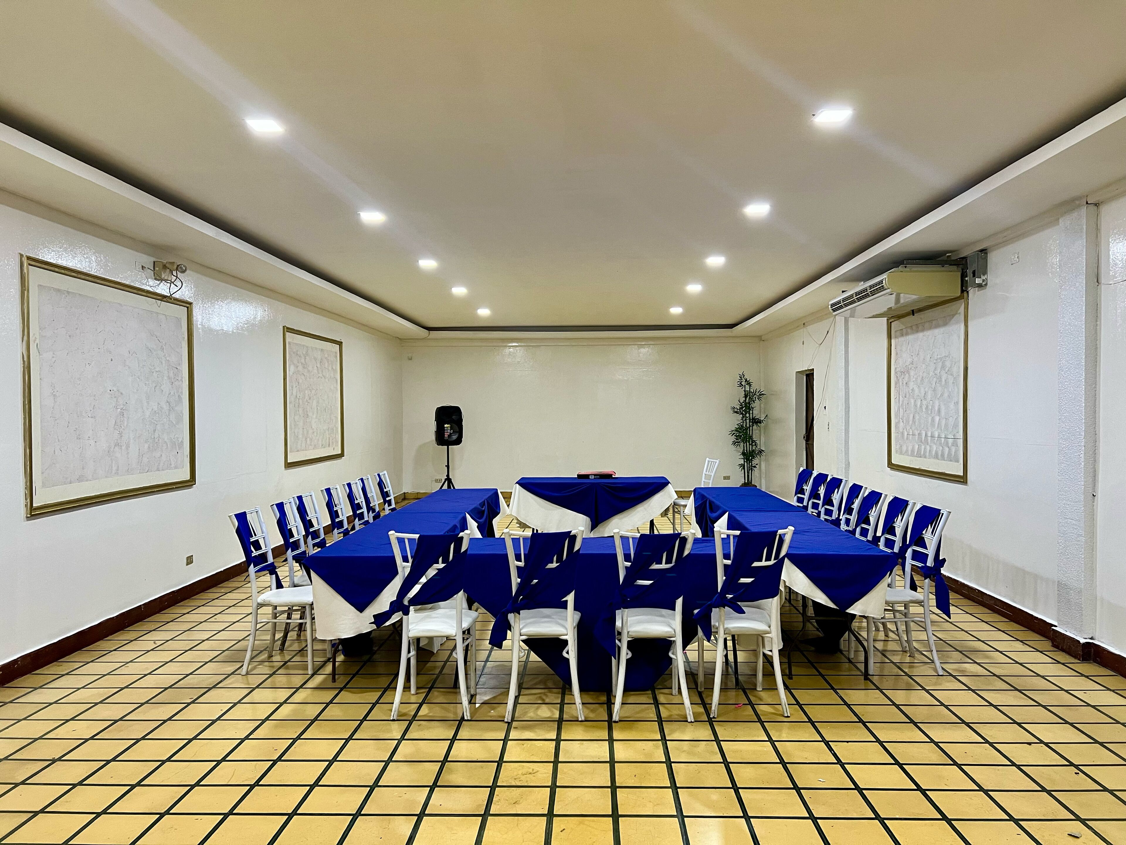A conference room with a long table, chairs, and a speaker.