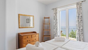 A bedroom with two beds, a wooden dresser, a ladder, a mirror, and a balcony with curtains. - Stunning, Beautiful Villa. Breathtaking Sea Views. Sandy Beaches (Lourdata)