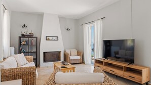 A living room with wicker furniture, a fireplace, a television, and a bookshelf. - Stunning, Beautiful Villa. Breathtaking Sea Views. Sandy Beaches (Lourdata)