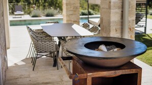 Eine Terrasse im Freien mit einem Metall-Feuerkorb, einem Tisch und Stühlen.