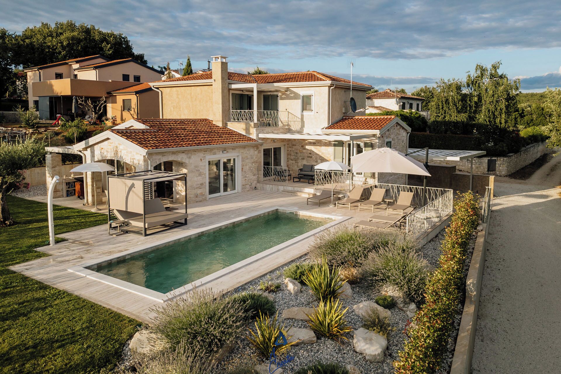 A modern villa with a swimming pool, outdoor seating, and a stone facade.