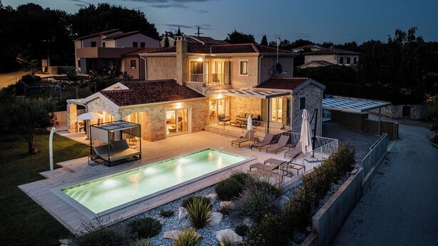 Eine moderne Villa mit Schwimmbad, Außenbereich mit Sitzgelegenheiten und einer gut beleuchteten Terrasse.