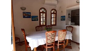 A dining room with a table set for four, wooden chairs, and two arched windows with decorative glass panes. - Exceptional view + large apartment overlooking the Bay of Algiers (Wilaya d'Alger)