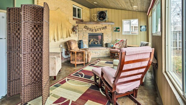 A cozy living room with a fireplace, wooden furniture, and a large window. - Shared Patio & Fire Pit: Denver Apartment (Denver)
