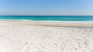 En sandstrand med fotspår som leder ner mot vattnet.