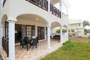 Un bâtiment à deux étages doté d’un patio couvert, aménagé avec du mobilier d’extérieur et un sol carrelé.