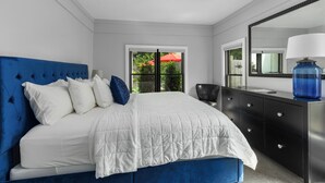 Un dormitorio con cama, ventilador de techo, cómoda y ventana con vista a la vegetación.