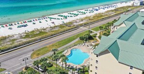 A resort with a pool, beach, and a road.