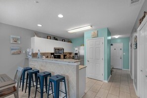 A kitchen with a bar area, white cabinets, and a teal accent wall.