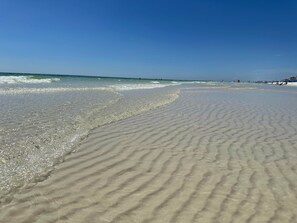 A sandy beach with gentle waves and a clear sky.
