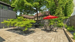 A patio with a red umbrella, a grill, and a small tree. - Perfect 2-Bedroom Suite in Downtown Saugatuck! (Upper Level Unit) (Saugatuck)