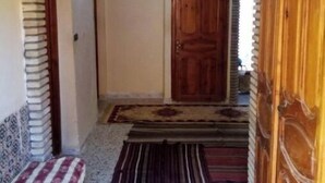 An arched doorway leading to a room with a patterned rug and a wooden door. - Dar Naftah, la belleza del sur de Túnez, una perla (Nefta)