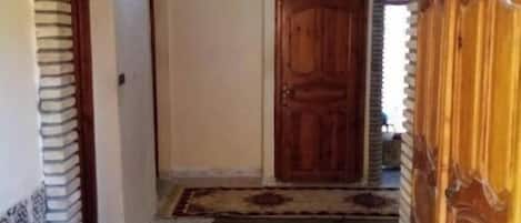 An arched doorway leading to a room with a patterned rug and a wooden door.