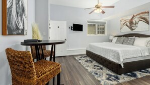 A bedroom with a bed, a ceiling fan, a TV, a window, and a door. - Studio in Downtown  (Haven Suites · Saugatuck) (Saugatuck)