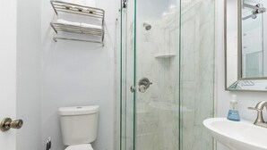 A bathroom with a glass-enclosed shower, a toilet, a sink, and a towel rack. - Studio in Downtown  (Haven Suites · Saugatuck) (Saugatuck)