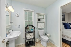 A bathroom with a sink, toilet, towel rack, and a clock on the wall. - Gorgeous 3BR, 2BA; The Perfect Home Away From Home! (Downtown Saugatuck) (Saugatuck)