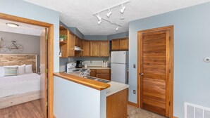 Eine kleine Küche mit Holzausstattung, einem Kühlschrank und einer Arbeitsplatte.