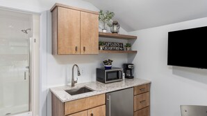 Une cuisine avec des meubles en bois, un réfrigérateur en acier inoxydable, un four à micro-ondes, une machine à café et une pancarte sur laquelle on peut lire : « CABINE DU CAPITAINE ».