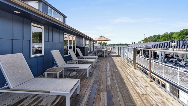 A deck with sun loungers, a table, and a view of the water.