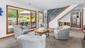 A modern interior with a seating area, large windows, and a staircase.
