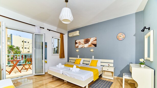 A modern hotel room with a large bed, a desk, and a balcony with a table and chairs. - Lotus Studios (Hersonissos)
