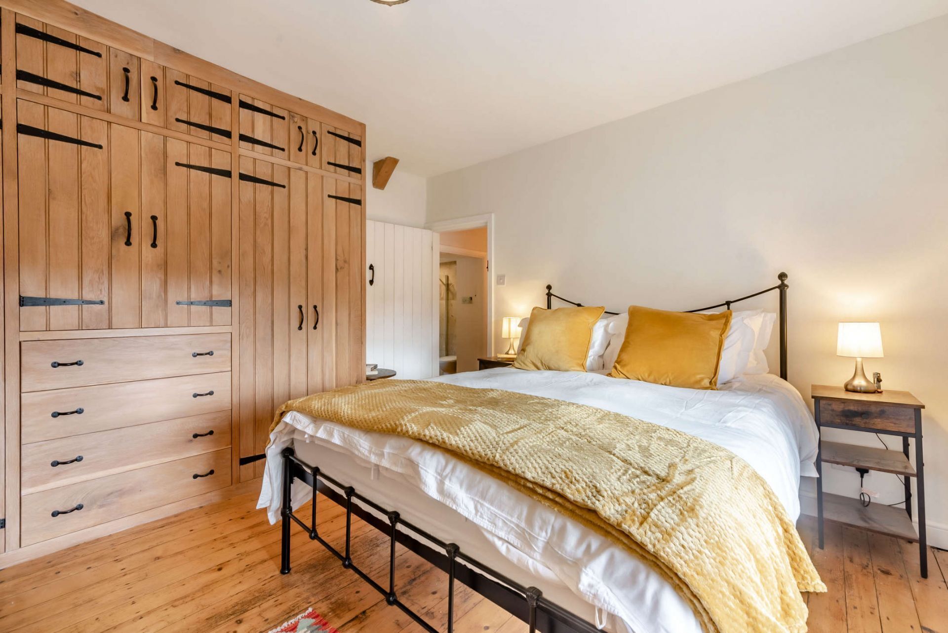 A bedroom with a bed, wooden wardrobe, and bedside table.