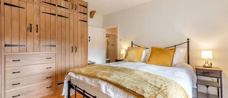 A bedroom with a bed, wooden wardrobe, and bedside table.