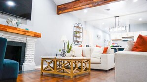 Un salon moderne avec une cheminée, un canapé, une table basse et un téléviseur fixé au mur.
