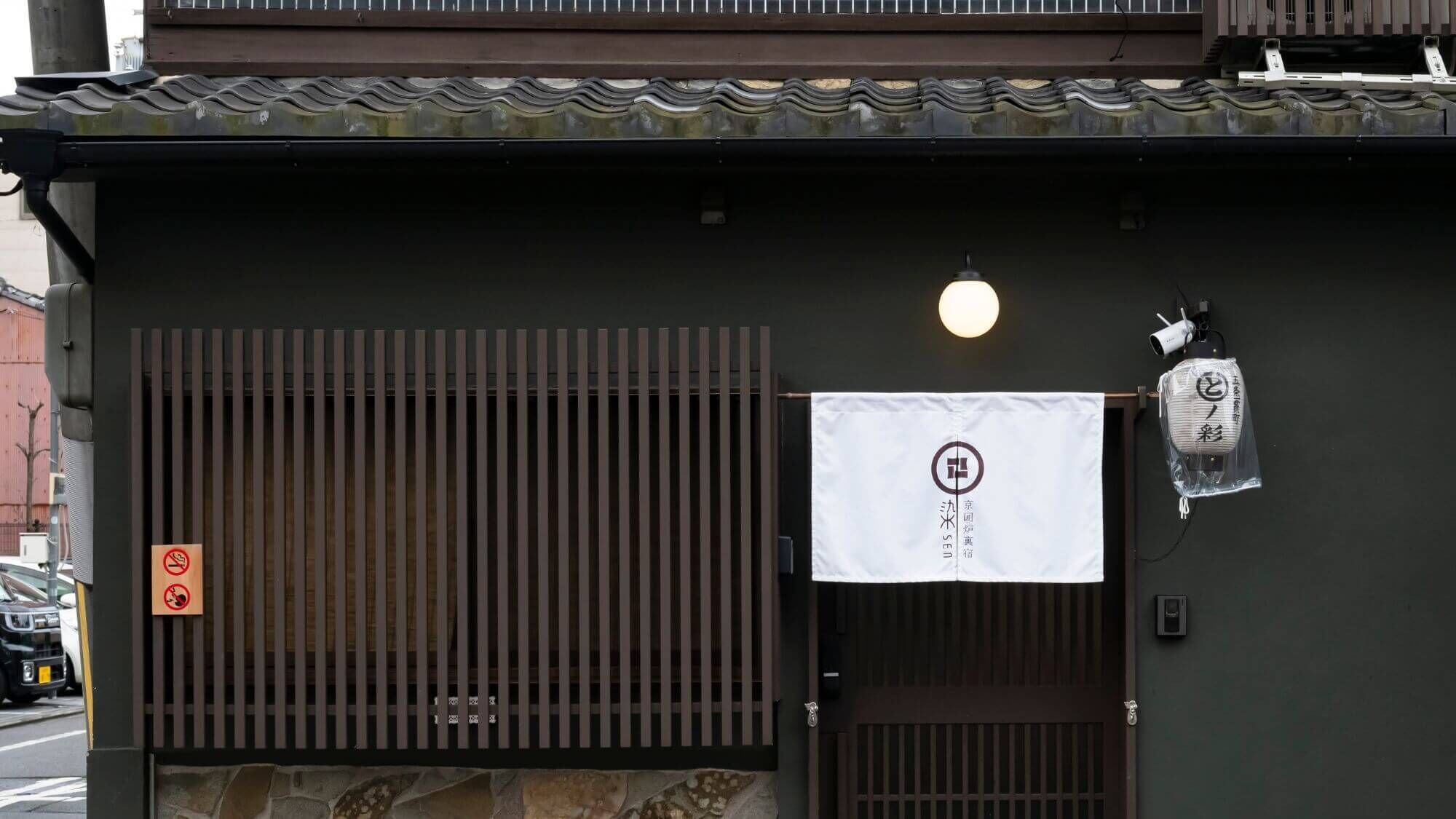 A building with a traditional Japanese entrance, a no-smoking sign, and a hanging lantern.