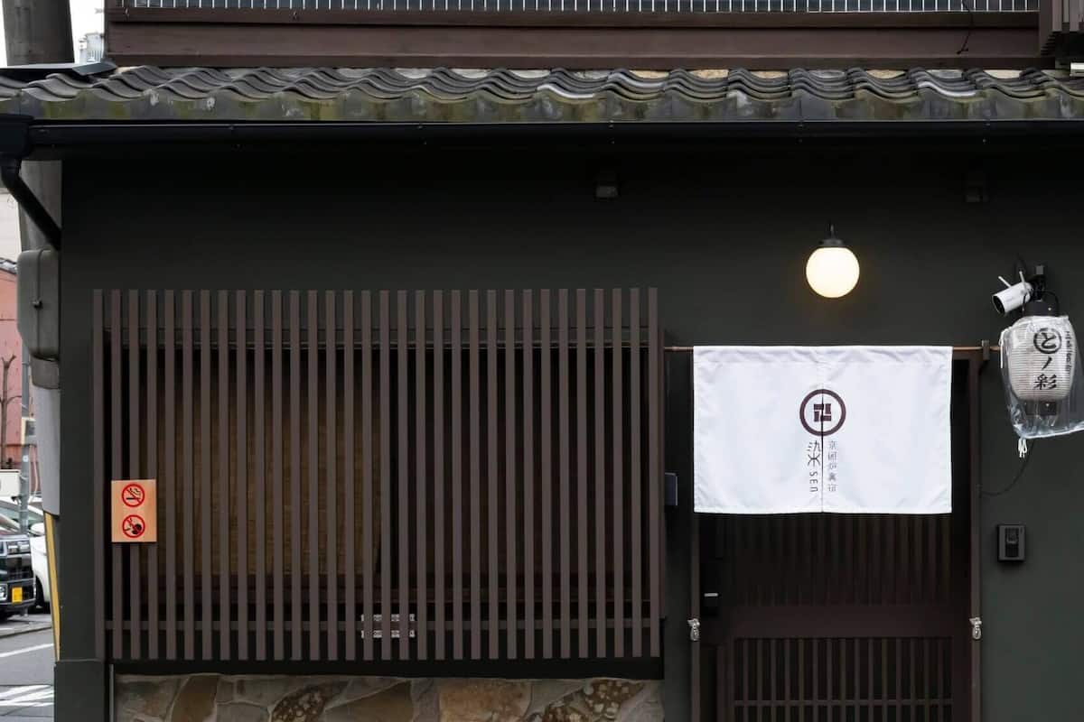 Een gebouwentree met een traditionele Japanse poort, een rookvrij bord en een hangend bord met Japanse tekens.