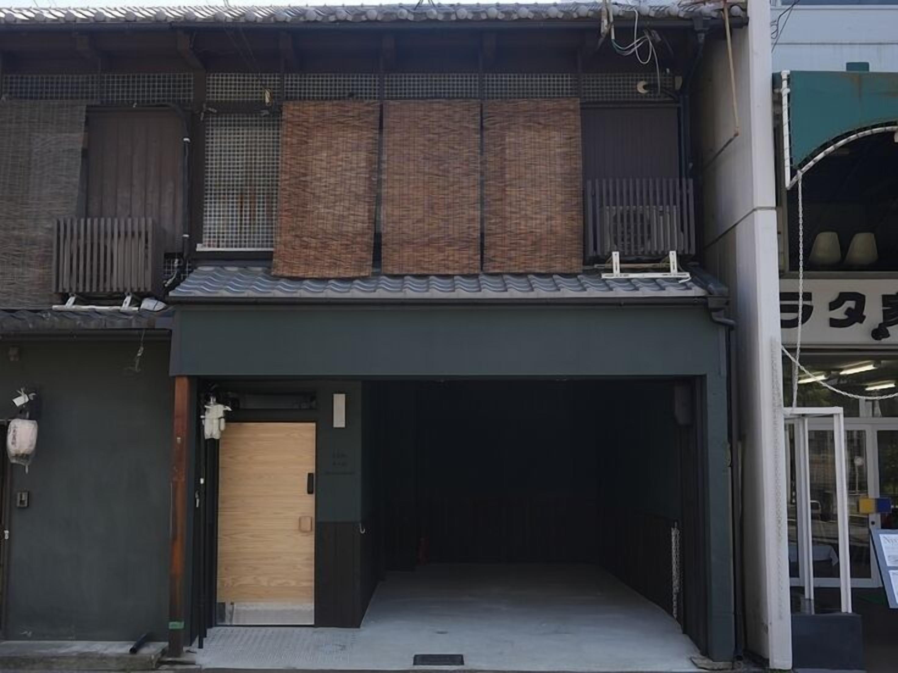 A building with a dark facade, a wooden door, and a covered entrance.