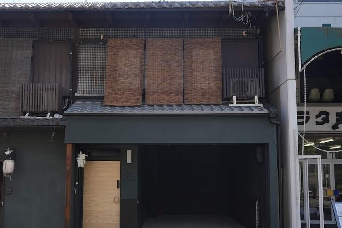 A building with a dark facade, a wooden door, and a covered entrance.