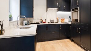 A modern kitchen with dark cabinets, a white countertop, and a wooden floor. - Wonderful Country Side Home, Winchester near River Test, Winchester Cathedral 6k (Winchester)