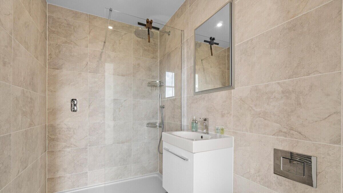 A modern bathroom with a glass-enclosed shower, a white sink, and a mirror on the wall.