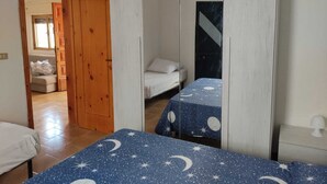 A bedroom with a bed covered in a starry night theme, a wooden wardrobe, and a mirror.